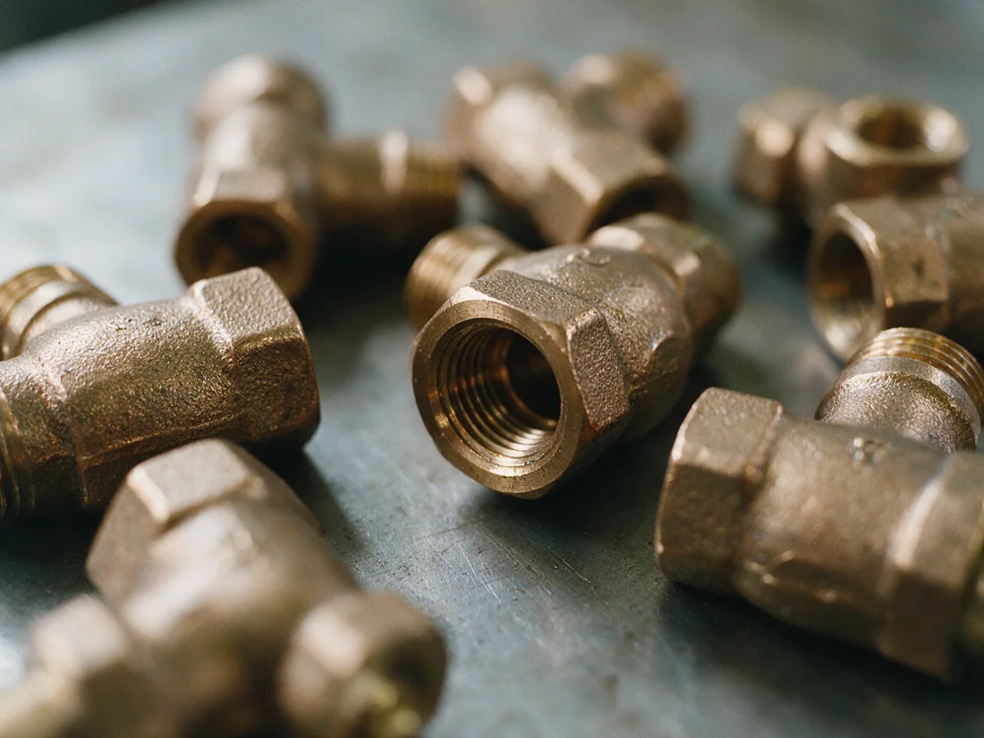 Close-up of small bronze threaded valves lying on a steel bench