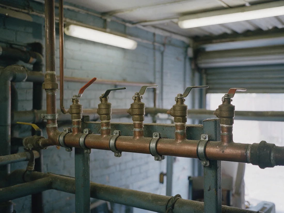 A row of small bronze lever ball valves teed off a horizontal header