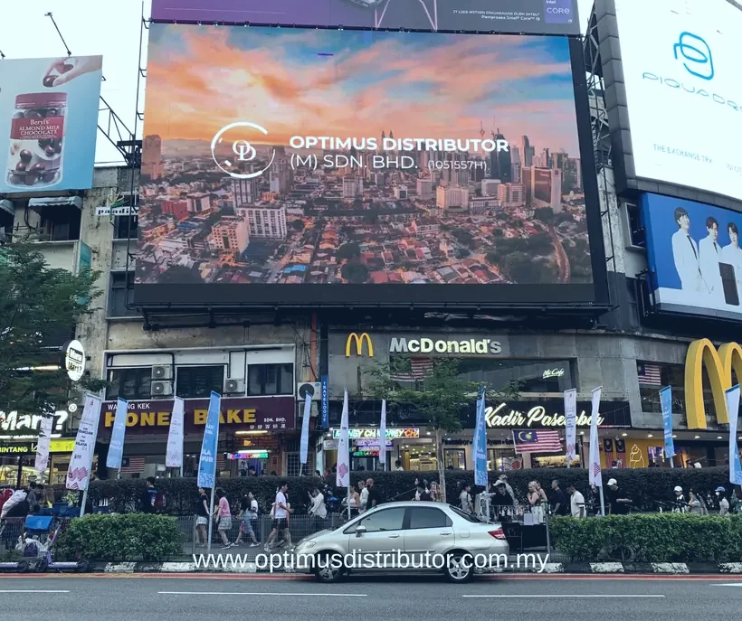 Optimus Distributor advertisement on a large digital billboard above a busy Kuala Lumpur street